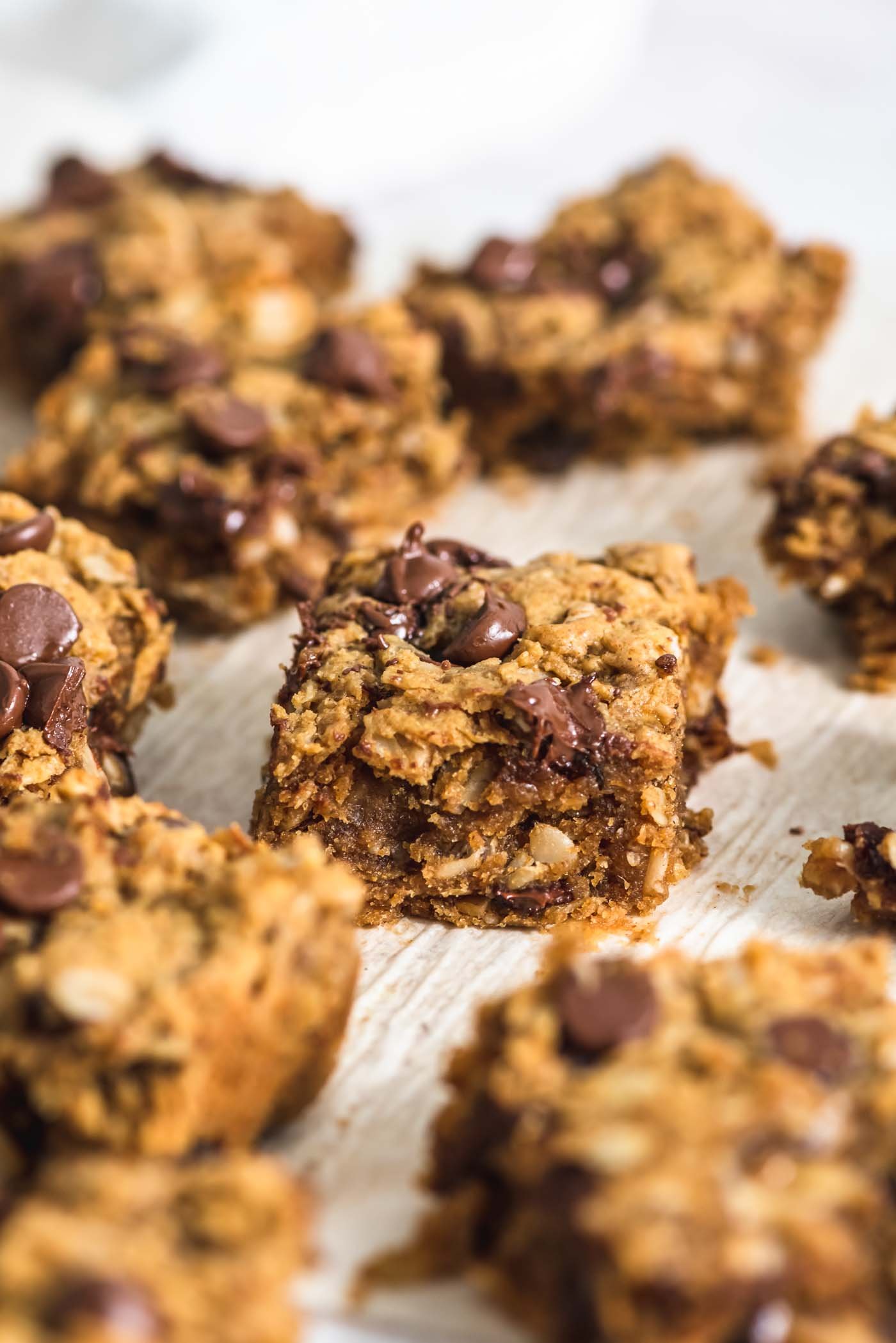 A number of peanut butter banana oatmeal chocolate chip cookie bars on a piece of parchment paper.