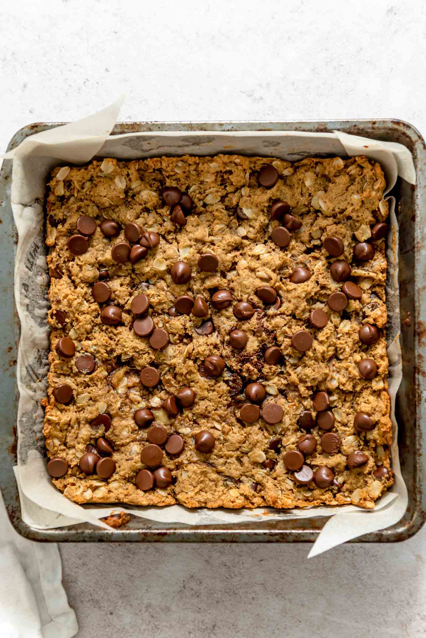 Overhead view into a pan of baked oatmeal chocolate chip cookie bars.