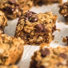 A number of peanut butter banana oatmeal chocolate chip cookie bars on a piece of parchment paper.