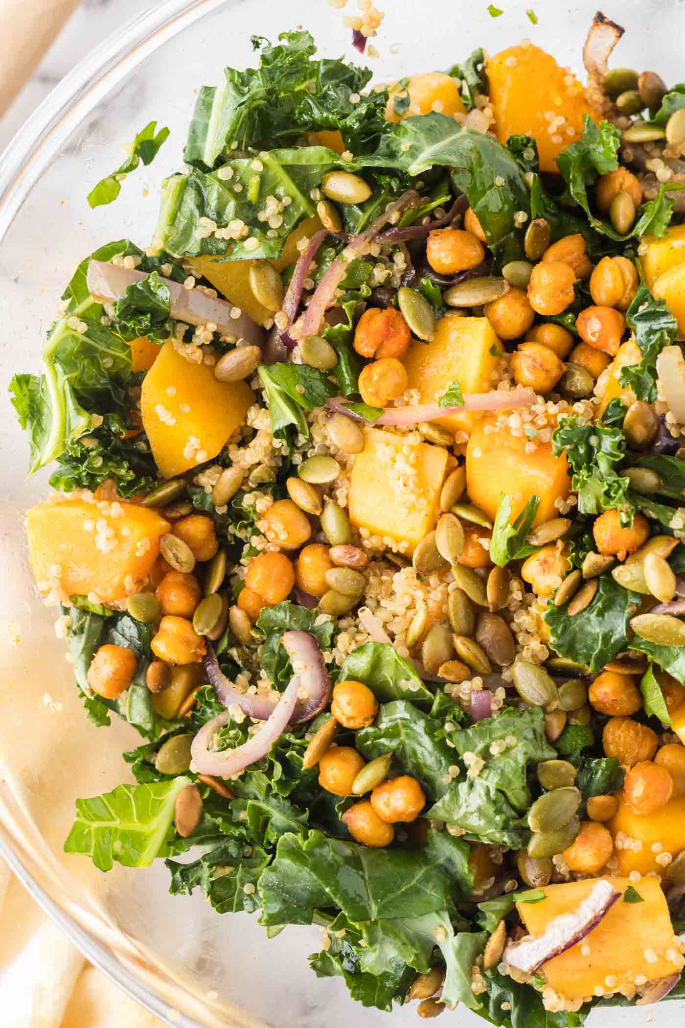 Close up overhead view of a bowl of kale quinoa salad with butternut squash, chickpeas, red onion and pepitas.