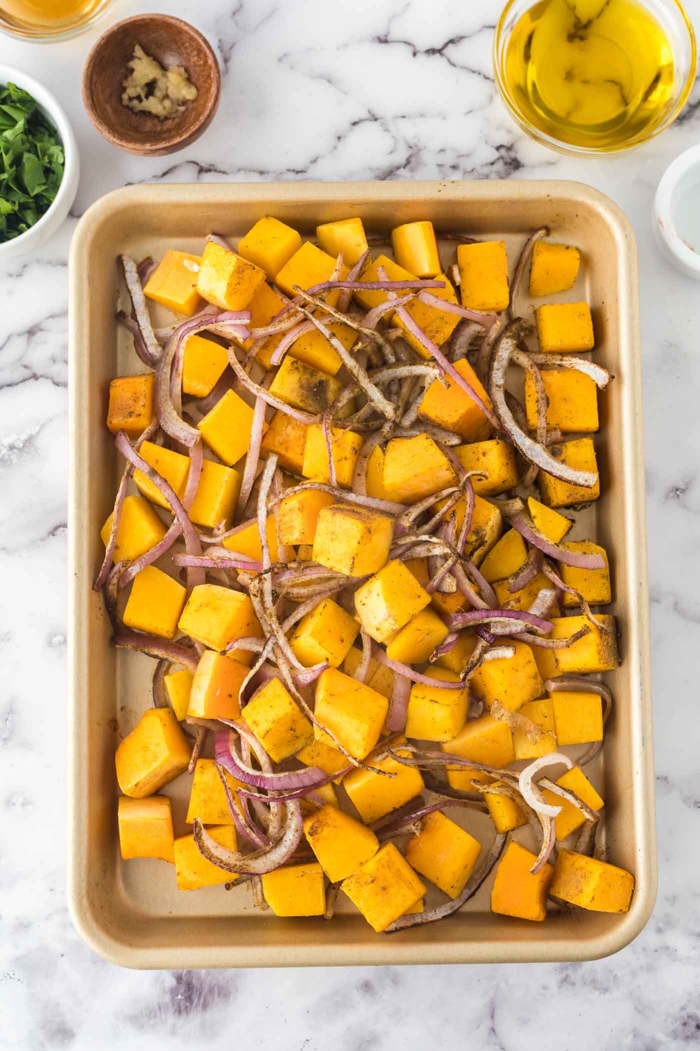Roasted cubes of squash and red onion on a baking tray.