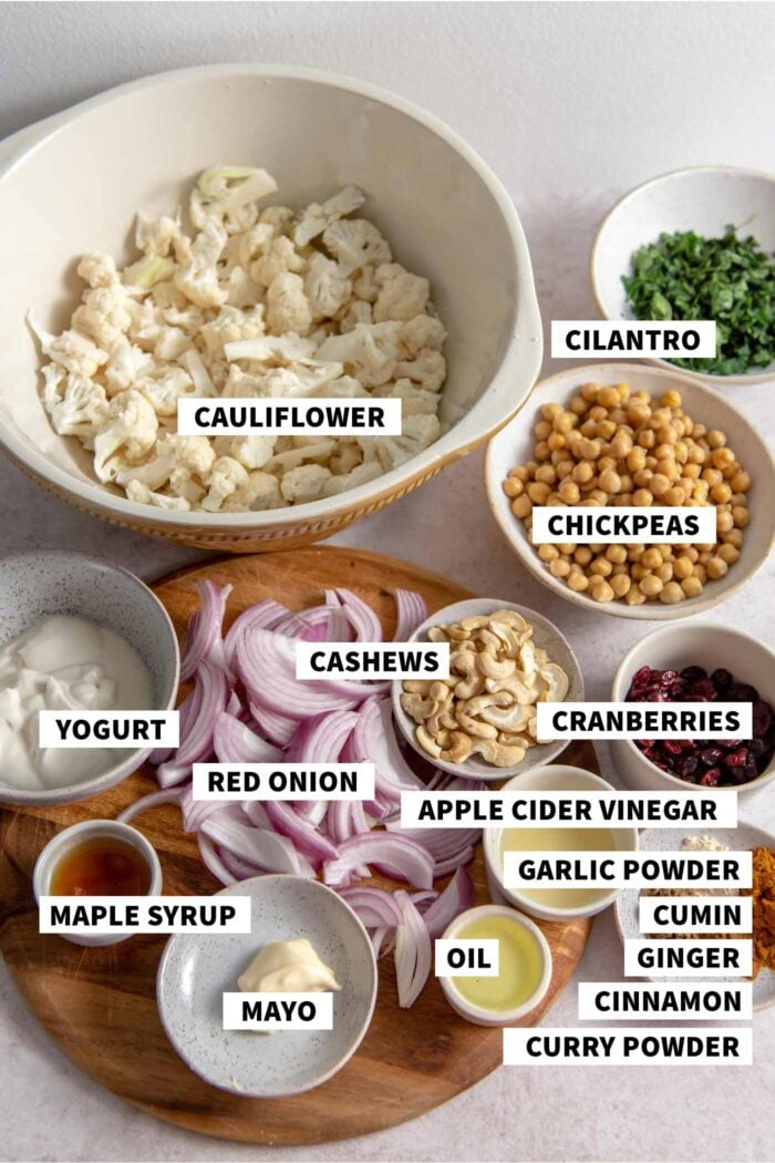 All of the ingredients needed for making a curry roasted cauliflower salad recipe with cashews, chickpeas, red onion and yogurt dressing.