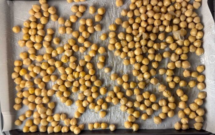 Chickpeas on a baking pan lined with parchment paper.