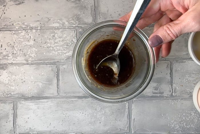 Spoon balsamic dressing into a glass bowl.