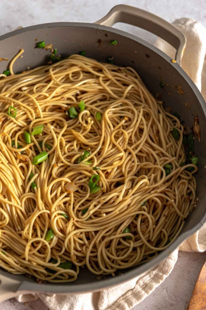 Chili oil noodles with green onions in a large skillet.