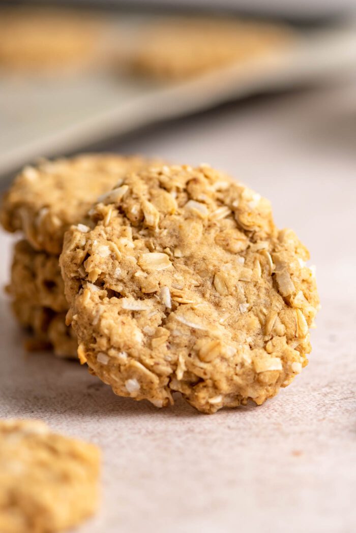 An oatmeal coconut cookie rests on top of a stack of 3 more cookies below it.