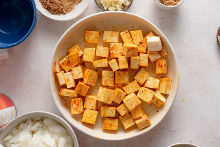 Cubes of tofu coated in turmeric and paprika in a bowl.