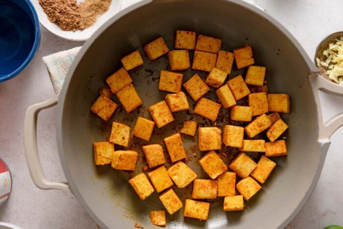 Cubes of tofu cooking in a skillet.