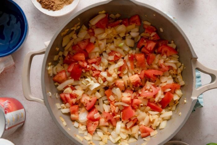 Tomato, onion and garlic cooking in a skillet.