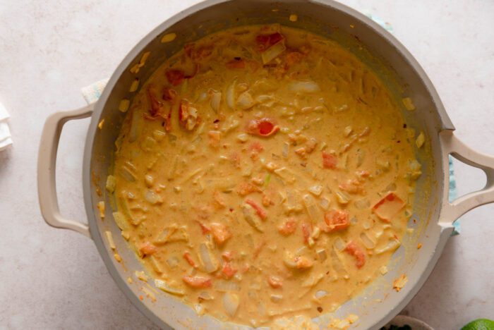 Diced tomato and onion cooking in a creamy coconut curry sauce.
