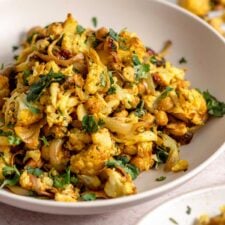 Curry roasted cauliflower salad with chickpeas, cashews, red onion and cilantro in a bowl.