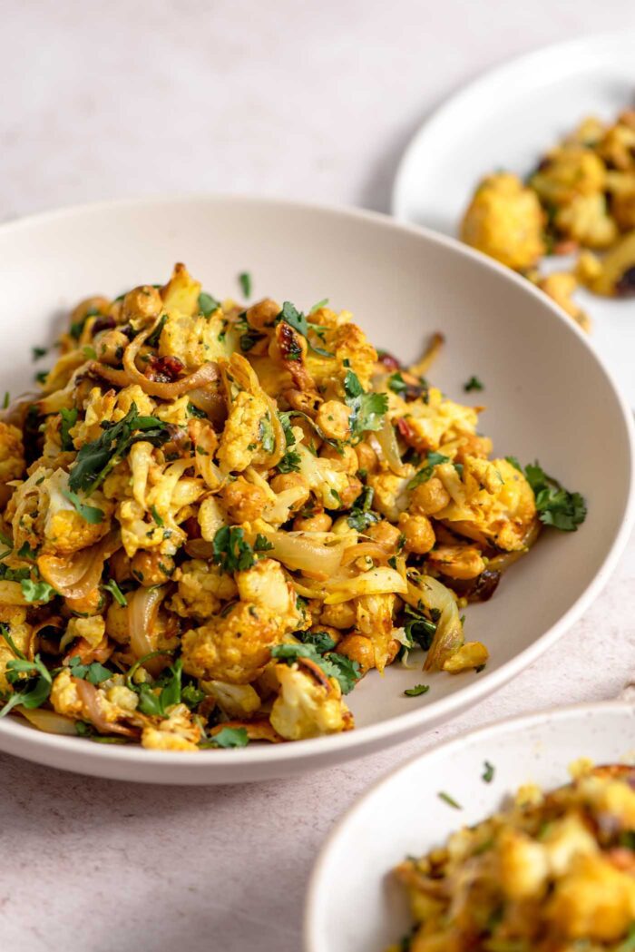 Curry roasted cauliflower salad with chickpeas, cashews, red onion and cilantro in a bowl.