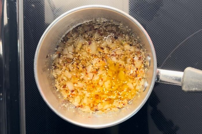 Garlic chili oil with sesame seeds in it in a small pot.