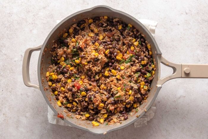 Rice, beans, corn and salsa mixed and cooking in a skillet.