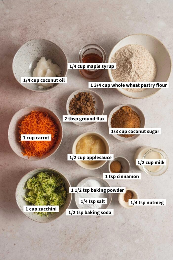 All the ingredients to make the Carrot Zucchini Muffins are assembled in several small dishes.  Each element is labeled in the text overlay.