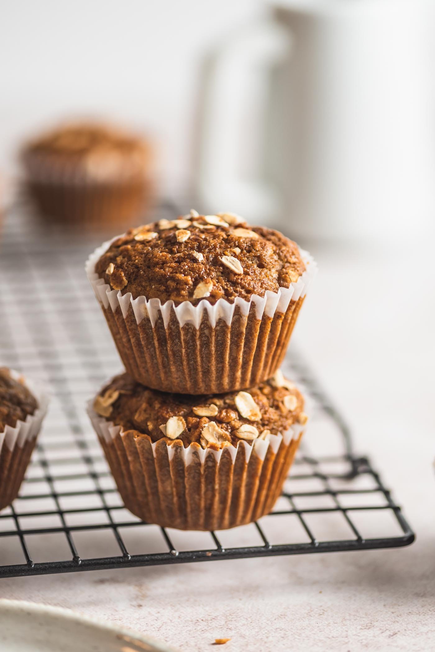 Stack of 2 oatmeal muffins on a baking cooling rack.