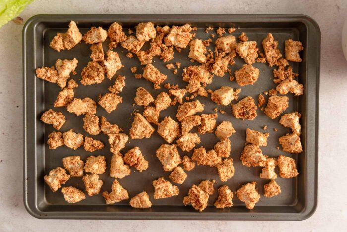 Crispy bits of tofu coated in spices and spread out on a baking sheet.
