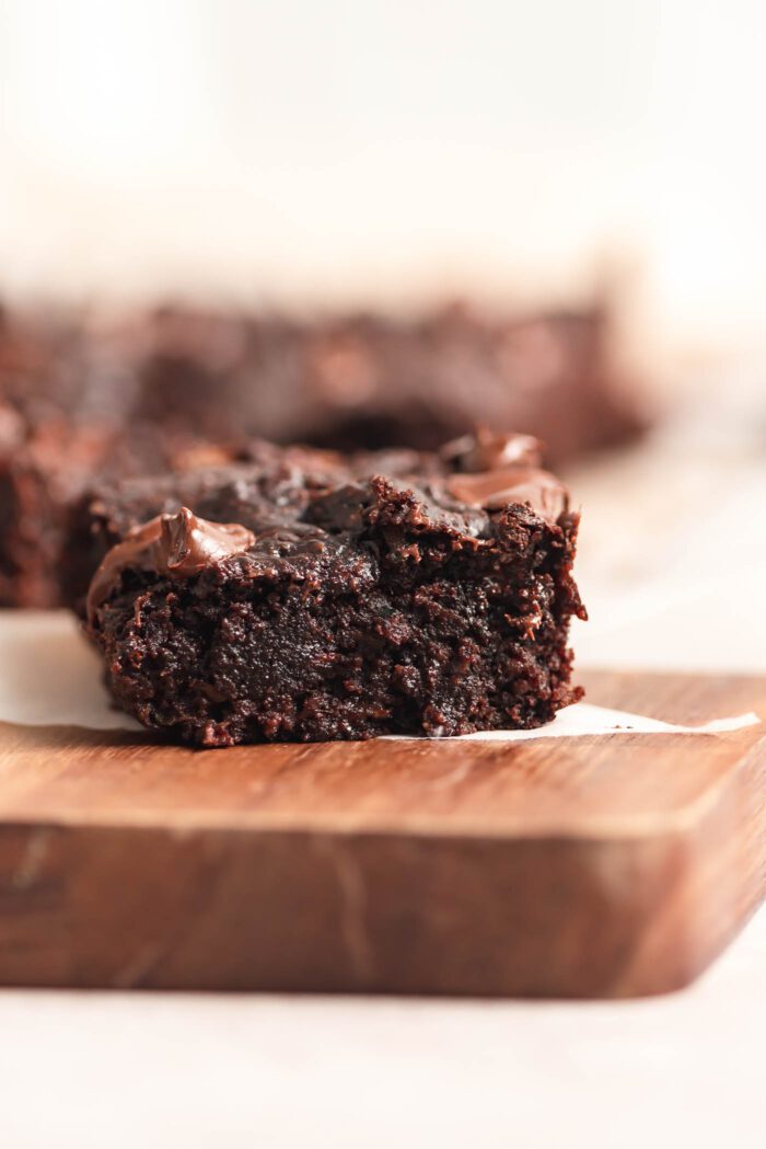 A fudgy chocolate chip zucchini brownie on a cutting board.