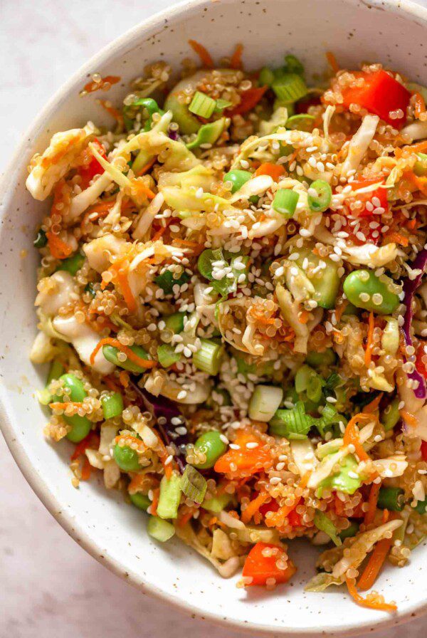 Overhead close up view of a bowl of quinoa salad with edamame, peppers, cabbage, carrot and green onion.