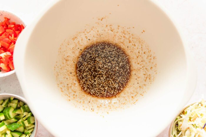 A soy ginger sesame dressing with sesame seeds in a large salad bowl.