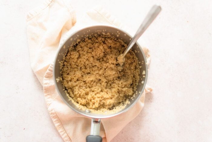 A pot of cooked quinoa with a fork in it.