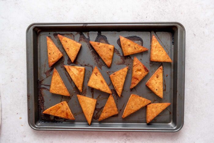 Roasted crispy tofu triangles on a baking sheet.