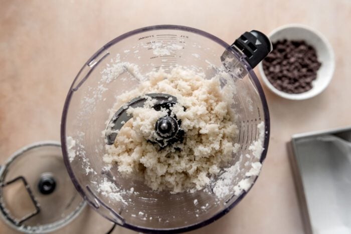 Blend coconut flakes in a food processor bowl.