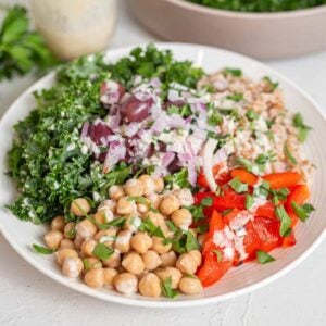 Bowl with farro, roasted red pepper, onion, olives, chickpeas, kale and dressing.