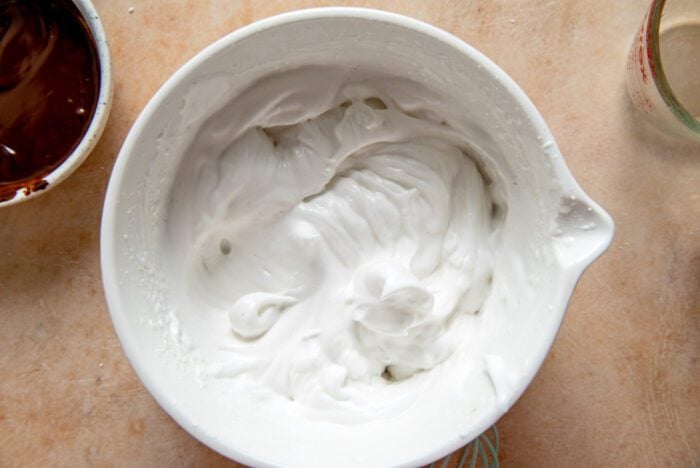 Whipped aquafaba with peaks formed in it in a mixing bowl.