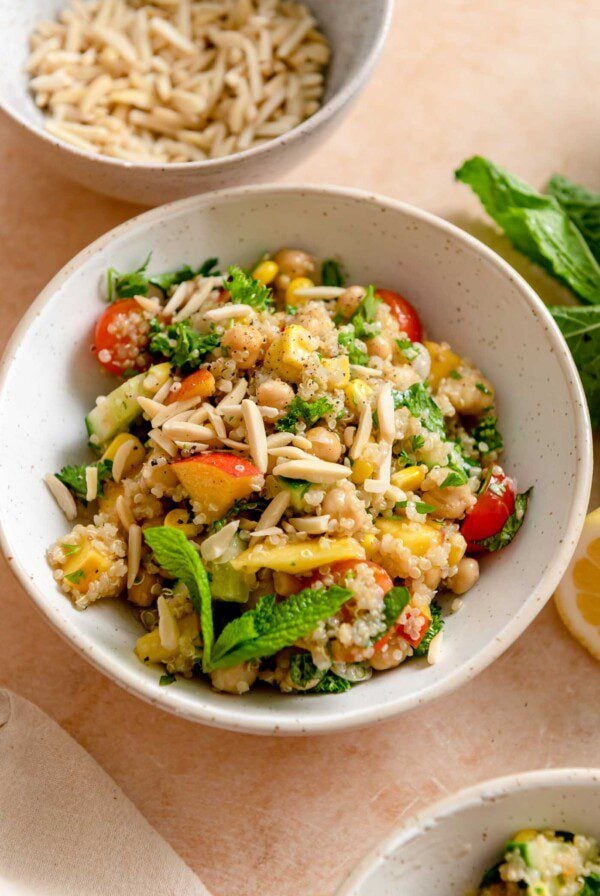 A bowl of a summer quinoa salad with nectarines, chickpeas, mint, almonds and cherry tomatoes.