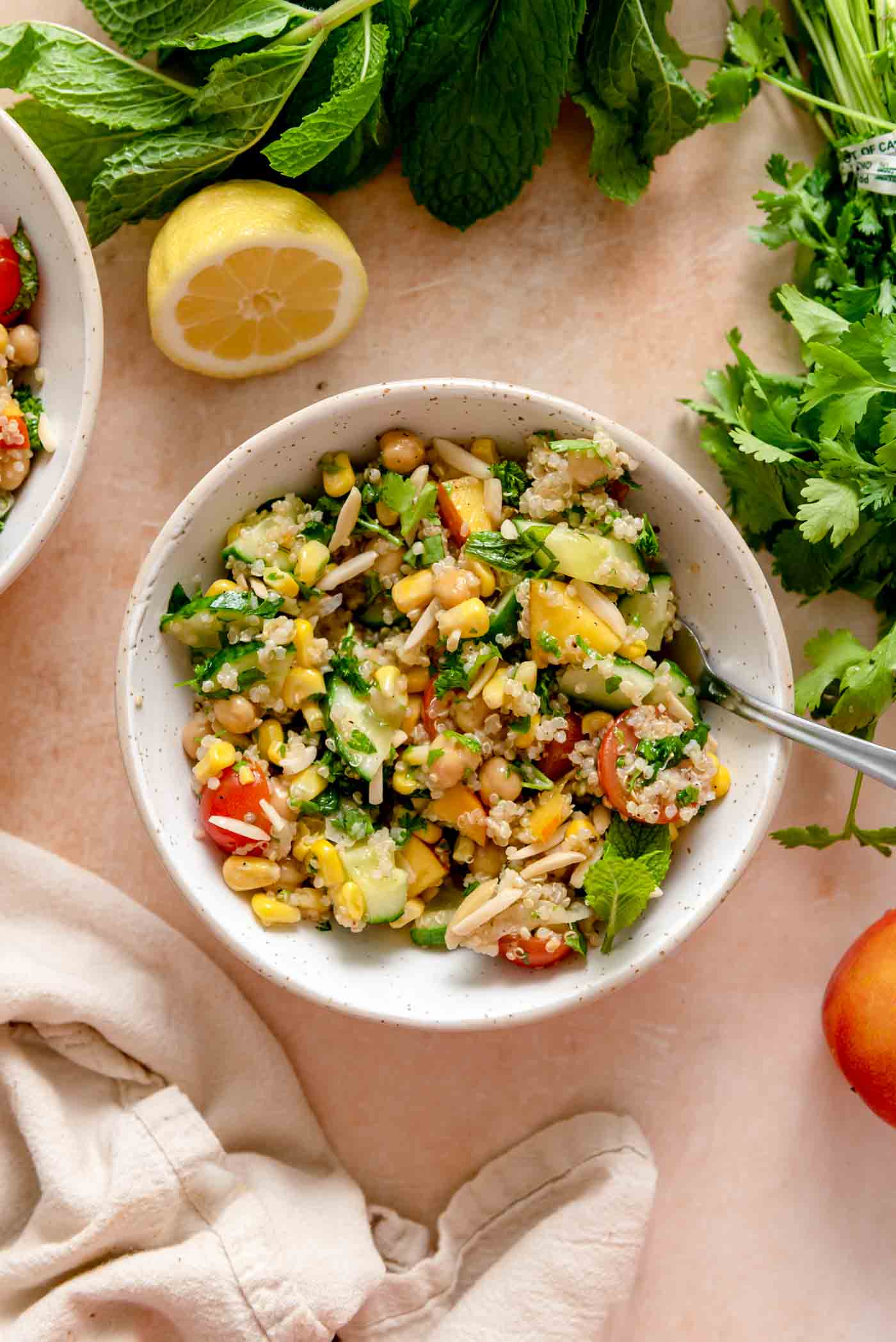 A bowl of a summer quinoa salad with nectarines, chickpeas, mint, almonds and cherry tomatoes.