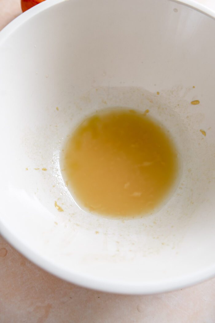 A small amount of a vinaigrette salad dressing in a large mixing bowl.