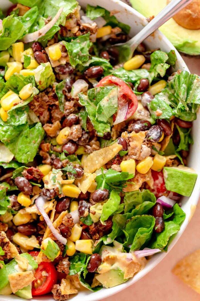 Taco salad with walnut-mushroom crumbles, lettuce, corn, red onion, tomato, avocado, crushed chips and a creamy dressing.