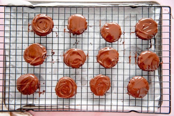 12 chocolate coated cookies on a baking rack placed over a baking sheet.