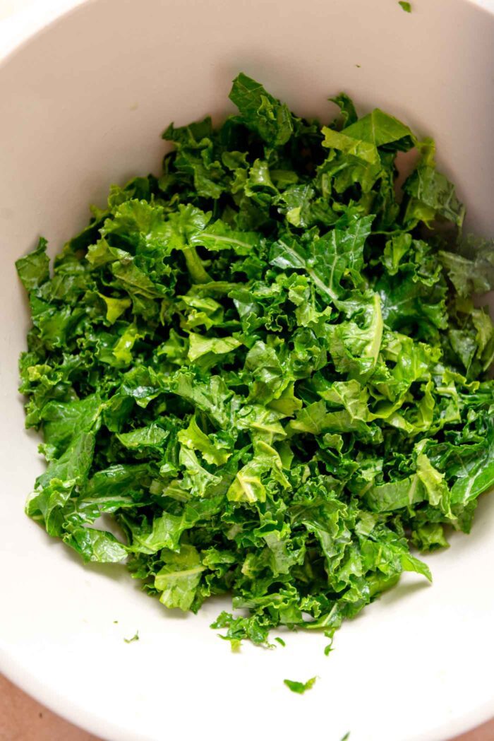 Chopped kale massaged with oil and lemon in a large mixing bowl.