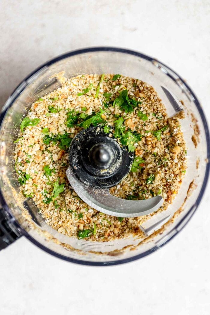 Blended mixture of breadcrumbs, oats, cilantro and black beans in a food prcoessor.