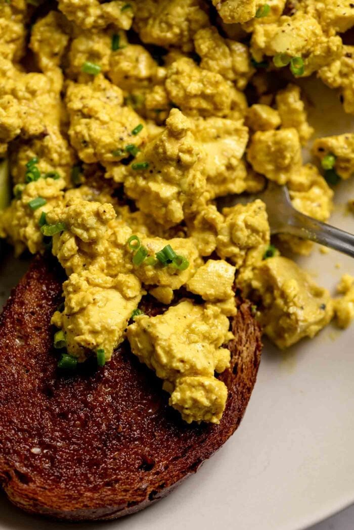 Bits of tofu scramble piled on a piece of toast in a bowl.