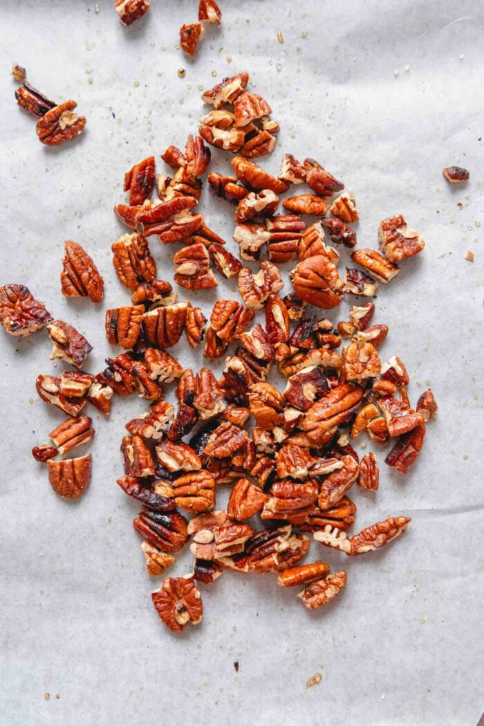 Candied chopped pecans on a baking sheet lined with parchment paper.