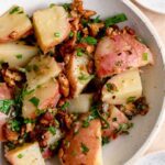 Bowl of warm potato salad with chives, parsley and tempeh bacon bits.