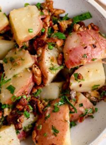Bowl of warm potato salad with chives, parsley and tempeh bacon bits.