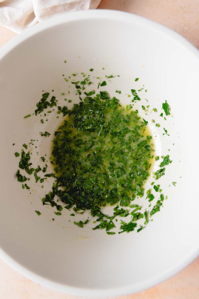 Vinegar-based herb dressing in a large mixing bowl.