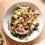 Freekeh salad with red onion, fennel, chickpeas, dates, walnuts and fresh herbs in a serving bowl.