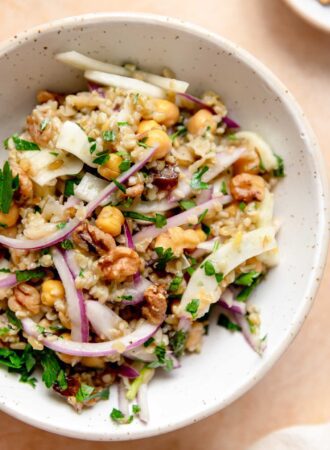 Bowl of freekeh salad with fennel, chickpeas, mint, parsley, dates, red onion and walnuts.