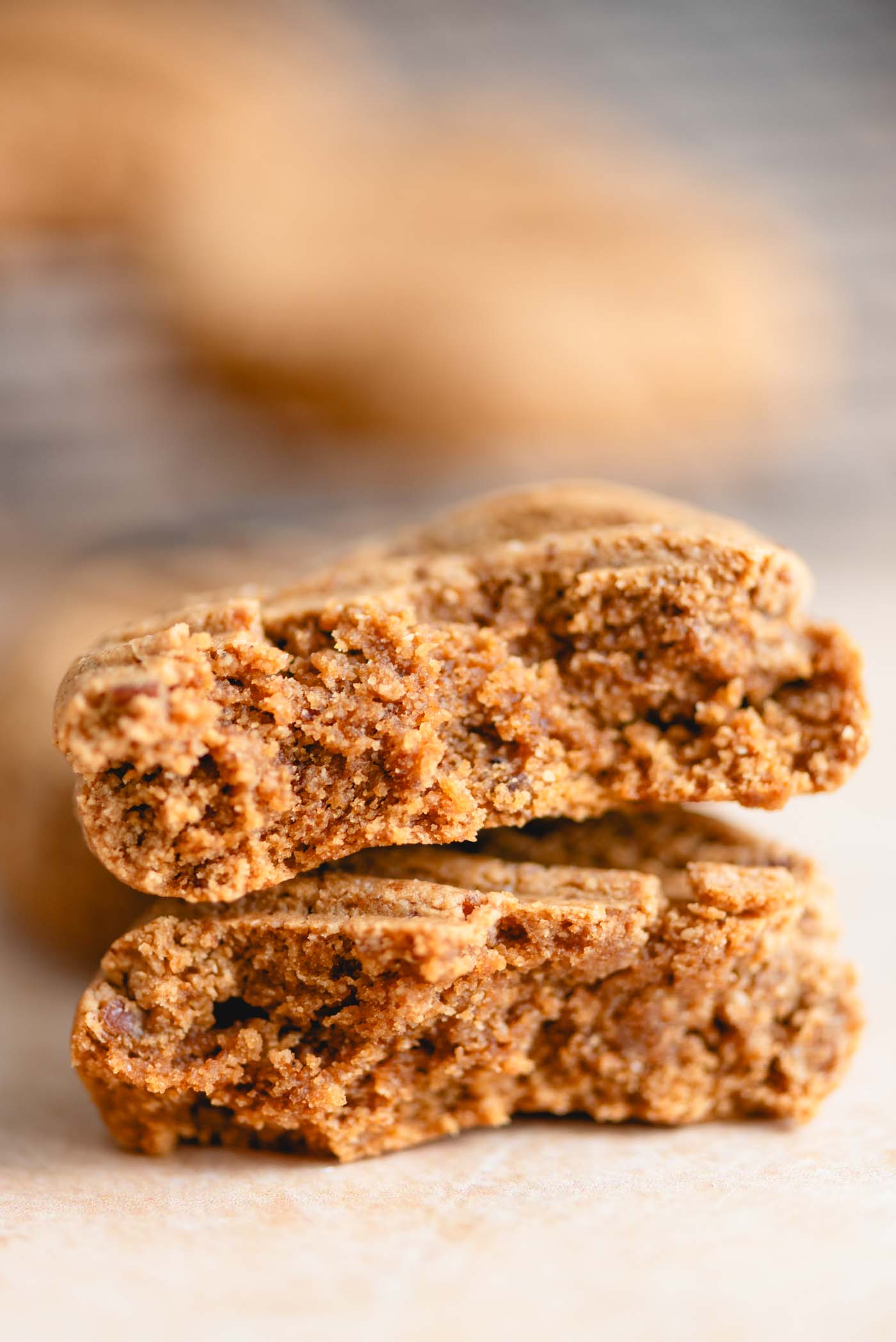 Peanut butter cookie broken in half and stacked on top of one another so you can see the inside texture of each half.