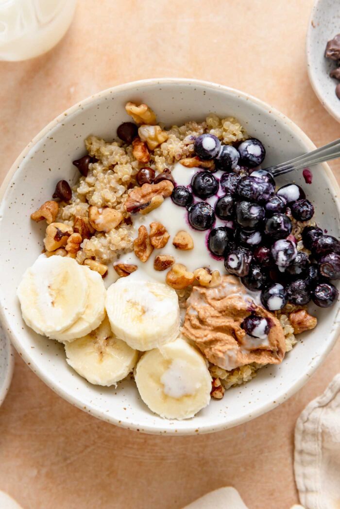 Quinoa breakfast bowl with banana, blueberries, walnuts, chocolate chips and yogurt.