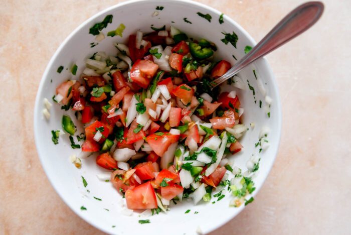 Mixing bowl of fresh salsa with onion, jalapeno and tomato.