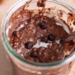 Jar of overnight chocolate protein oats with a few chocolate chips sprinkled over top.