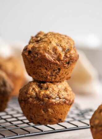 Two banana walnuts muffins stacked on top of each other on a wire rack.