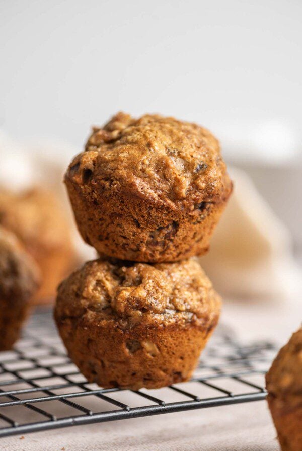 Two banana walnuts muffins stacked on top of each other on a wire rack.