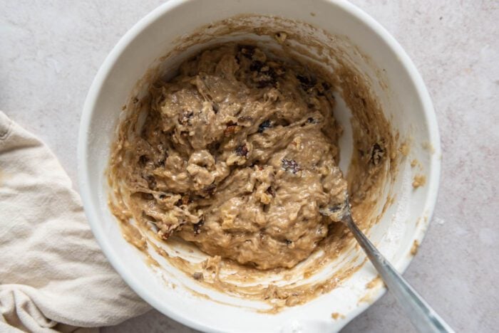 Banana walnut muffin batter in a mixing bowl with a spoon.
